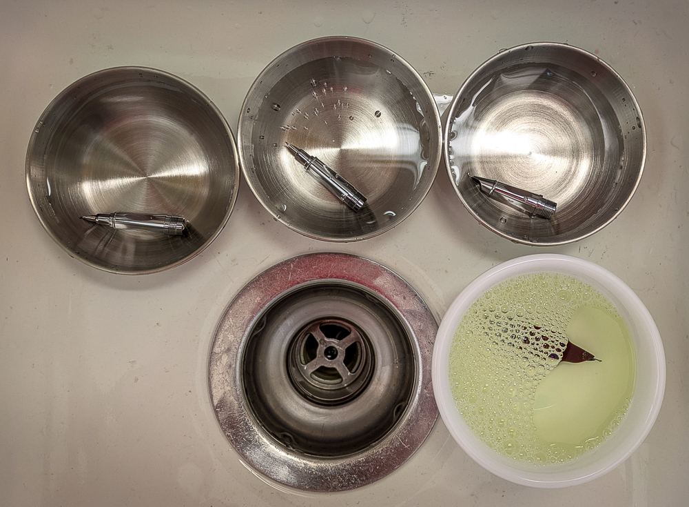 4 small dishes in a sink with a nib soaking in each